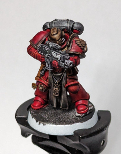 Warhammer 40k Space Marine Strenguard Veteran painted in a Blood Angels color scheme with red and black armor, brush helmet and details, and grey robes.