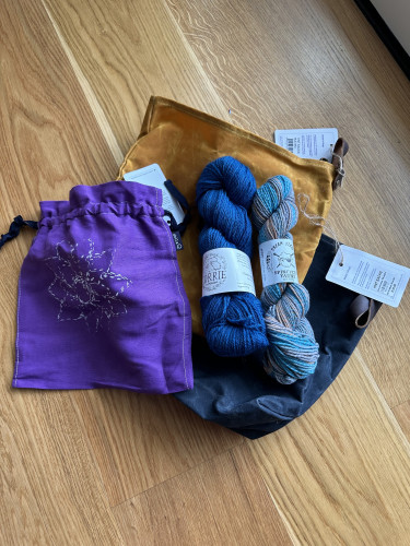 Purple project bag, mustard and blue makers sacks, and two skeins of yarn (blue from La bien Aimee, multicolor from Spincycle)