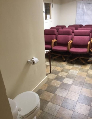 A bunch of conference room chairs facing a solitary toilet