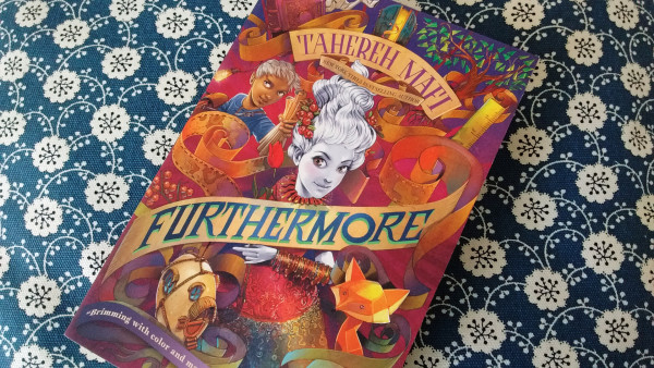 The book cover of Furthermore is a very colorful one. By contrast, at its center, the black and white portrait of a young woman pops to greet us with a smile. She's surrounded by colorful things. A fox made of hard angles, a boy dressed in blue and holding a map, a house in the shape of an egg, a tree with leaves of an impossible green. 