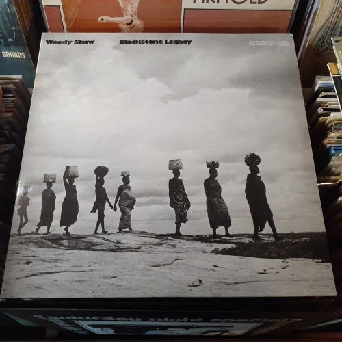 Album cover features a black and white photograph of African women in traditional dress, walking in a line, each with a basket or other item balanced on their head.