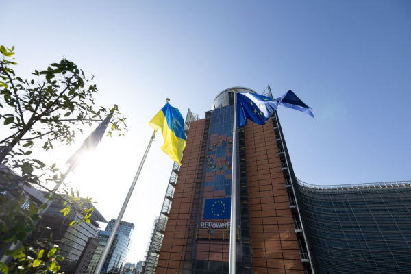 A tilt shot of the Ukrainian Flag standing between two EU flags in front of the European Commission's headquarters in Brussels, Belgium