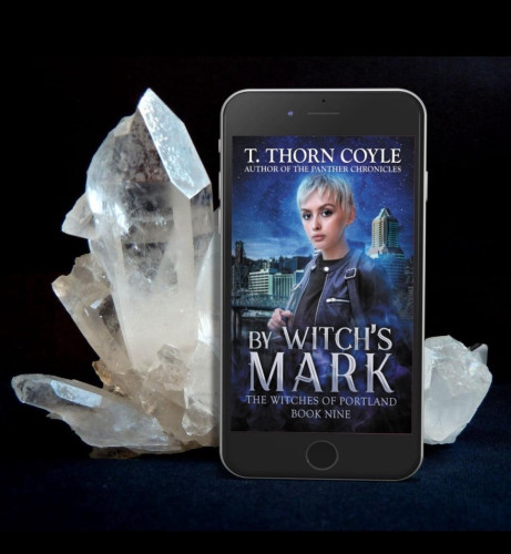 By Witch’s Mark book cover on a phone, leaning against a crystal.