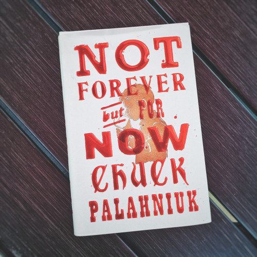 Chuck Palahniuk's new book "Not Forever But For Now" on a wooden table
