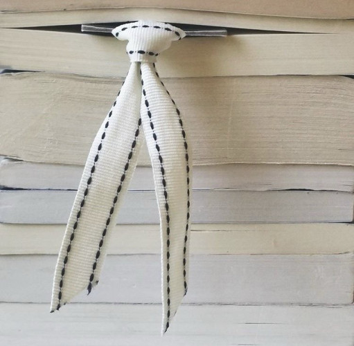 A close up of book pages, with a white ribboned bookmark hanging out.