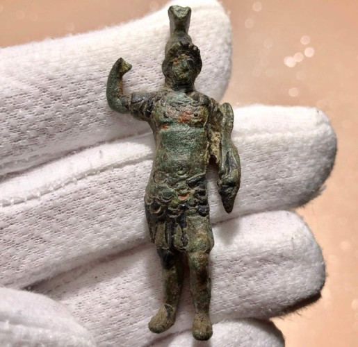 Bronze statuette of the god Mars with an olive green patina. The god has his right arm raised, probably to hold a spear that is now lost. He is in full armour with a crested helmet, a breastplate, and the protective leather skirt called pteryges.