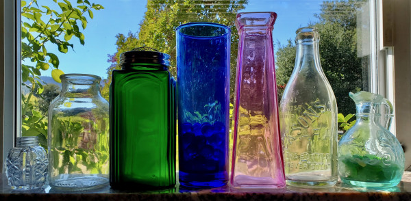 Clear and color bottles on a window sill.