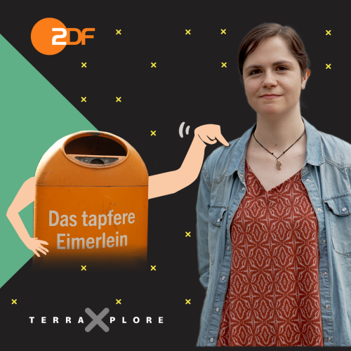 Thora Schubert steht rechts im Bild. Links von ihr befindet sich ein orangener Mülleimer mit der Aufschrift "Das tapfere Eimerlein". Der Eimer hat Arme und tippt Thora mit einem Arm auf die Schulter.