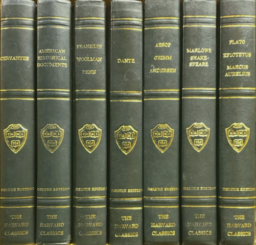 A photo of seven leather-bound hardcover Deluxe Edition volumes from the Harvard Classics. They are dark green with gold titling, as follows:

CERVANTES.
AMERICAN HISTORICAL DOCUMENTS.
FRANKLIN, WOOLMAN, PENN.
DANTE.
AESOP, GRIMM, ANDERSEN.
MARLOWE, SHAKESPEARE.
PLATO, EPICTETUS, MARCUS AURELIUS.