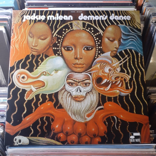 Album cover features a painting featuring a configuration of three women's faces at the top, with two masks (a pachyderm and a demon) below those,  and a sorr of skeleton mask with a beard at the bottom, just above an orange torso with nine breasts. It's pretty freaky.