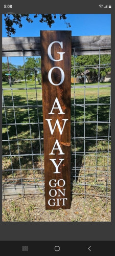 Wooden board with painted white capital letters that read "Go Away, Go on, Git" when reading down