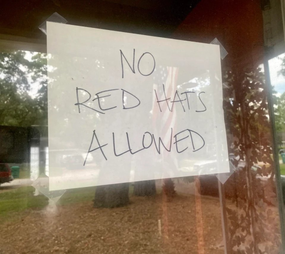 No RED HATS allowed sign on shop Window.