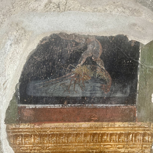 A fragment of a fresco scene on a black background seemingly showing a figure (one of the erotes perhaps?) balance on the back of a very large prawn.