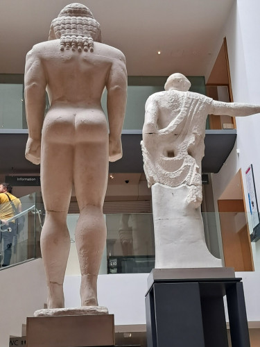 photograph of the backside of two Classical marble statues. One with a nicely formed buttocks, the other with an unfinished backside, with a large hole for attaching it to a wall
