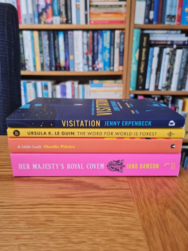 A stack of books, all with a hint of yellow in the cover or font.

Visitation by Jenny Erpenbeck
The Word for World is Forest but Ursula K Le Guin
A Little Luck by Claudia Piñeiro
Her Majesty's Royal Coven by Juno Dawson