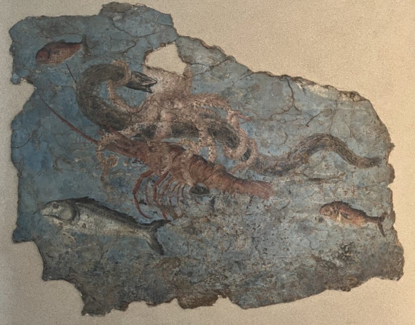 A fresco fragment with a blue background. A variety of sea life is depicted including three fish. The main action though is an octopus grappling with an eel and a crustacean at the same time in the centre of the fragment.