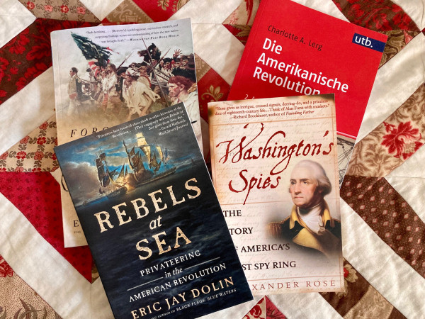 Books on a quilt blanket: i.a. Rose 'Washington's Spies', Lerg 'Amerikanische Revolution', Dolin 'Rebels at Sea'