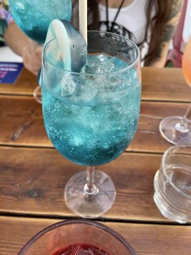 A cocktail glass with a blue liquid, ice, and a gummy shark