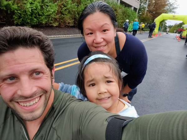 A selfie I took with my wife and daughter after running a 4 mile road race. The inflatable finish line is visible in the background.