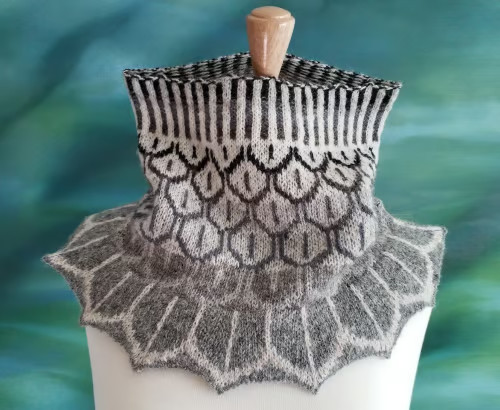 A cowl with neutral brown, gray, and white colorwork feathers and a flared bottom, making the cowl appear to be feathers integrating into the outfit.