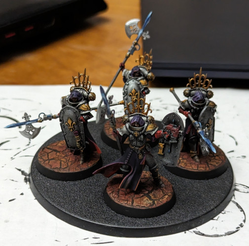 Warhammer 40k Adepta Sororitas Celestian Sacresants armed with anointed halberds. Metallic black armor with gold accents and purple robes with red trim. Now with red-planet bases and heads attached.