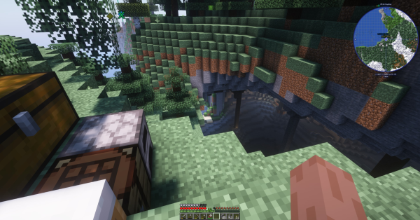 View from the top of a tree-lined crevasse: near foreground shows a bed, crafting table, furnace, and a big chest. Beyond that are pillars descending a few dozen meters to the base of a cavern.
