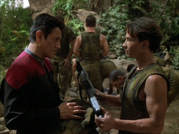 Chakotay accepting a weapon from a Vori soldier in the jungle
