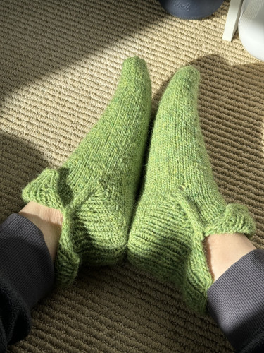 Green hand knitted slippers, front cuff folded down, back cuff up