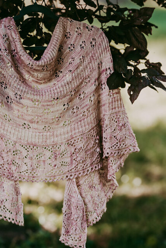 Photo of a knitted  crescent shawl using different lace patterns-flowers & leaves, and ribbing, stocking stitch.