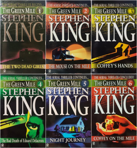 A composite photo of all six books of Stephen King's "The Green Mile" serialized novel, as follows:

1) "The Two Dead Girls" - The serial thriller begins. A silhouette of an old prison.
This edition of this volume has the author's name embossed with silver metallic letters.

2) "The Mouse on the Mile" - The serial thriller continues. An old prisoner transport truck drives along a lonely road.

3) "Coffey's Hands" - The serial thriller continues. A man's long shadow ominously covers a medium-sized dog house with an empty leash hanging from it's doorway.

4) "The Bad Death of Edward Delacroix" - The serial thriller continues. A cropped close-up of a man's face, showing only his nose, right eye, and corresponding cheekbone in front of the long shadow of an electric chair.

5) "Night Journey" - The serial thriller continues. A nice small house at night with a single room illuminated from within.

6) "Coffey on the Mile" - The serial thriller concludes. A close-up of a man's hand, palm up, thumb raised, with a white mouse inside.