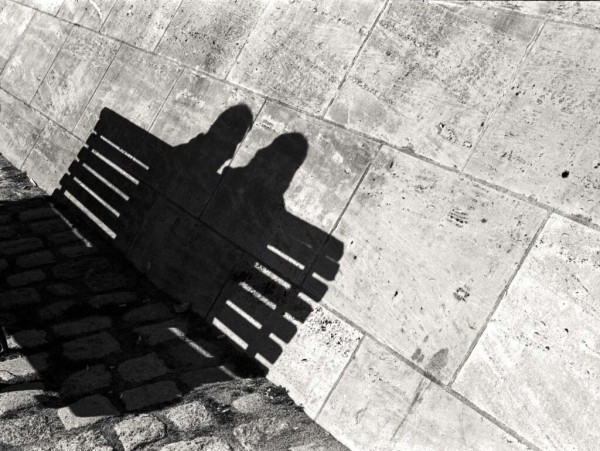 Dert Schatten einer Bank, auf der zwei Menschen sitzen