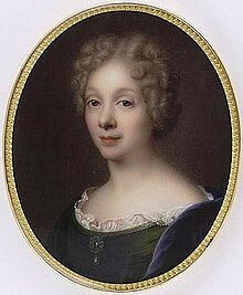 A painted portrait of Anne Dacier. She is looking serenely at the viewer. She has a small smile and she wears her light hair curled close to her head. She has on a dark colored gown with a delicate lace collar. 