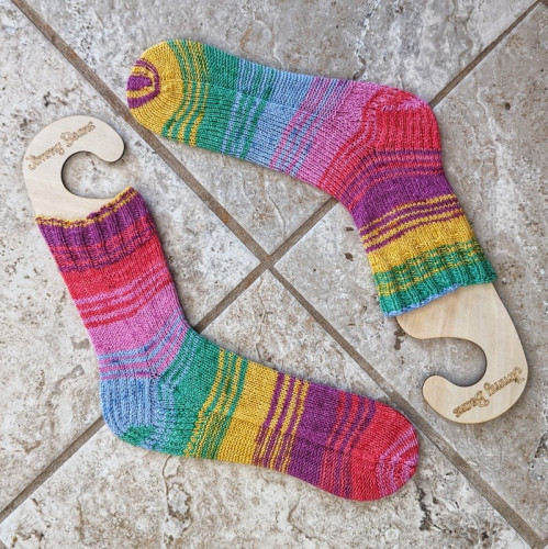 A set of two fraternal handknit socks with rainbow ish stripes. They have been blocked on sock blockers.