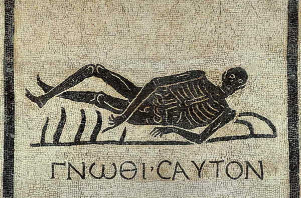 Detail from a white mosaic with a black border. In the central a black skeleton reclines on something. Beneath them is the Greek phrase ‘gnōthi sauton’ (know thyself).