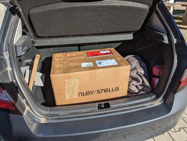 A paper box inside the trunk of a car. Inside: Metalhead.club T-shirts