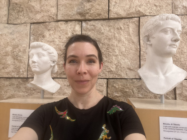 Dr G standing between a bust of Livia and Tiberius at the Ara Pacis Museum.