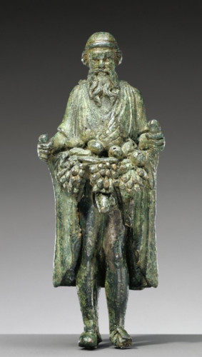Description from museum: “Small figurine of Priapus, the god of fertility. He has a flowing beard, deeply-set eyes and wears a cap on his head. With sandals on his feet, he is dressed in a long-sleeved tunic and himation. Priapus grasps the sides of his garment, lifting it upwards to create a deep fold that overflows with masses of fruit and agricultural produce. In lifting his himation, he reveals his enormous phallus, creating a vivid connection between fertility and abundance.”