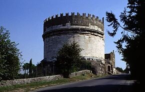 Cecilia Metella  tomb on the Appian Way , gigantic marble cylindrical monument topped by medieval battleways among trees on a blue sky 