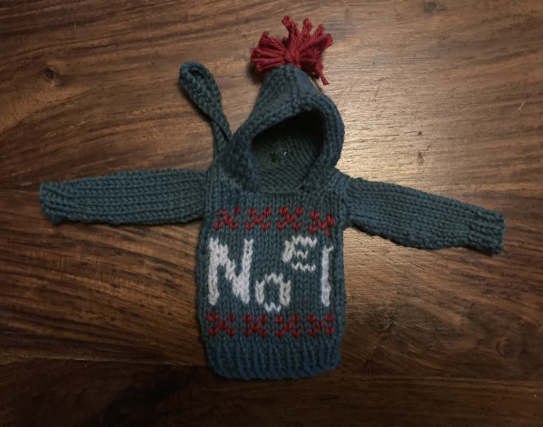 Knitted Xmas tree decoration - a tiny Christmas jumper with the word Noel on the front and a red pompon on the hood