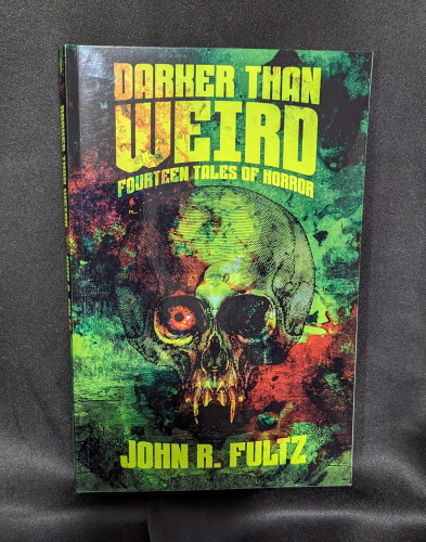 Paperback of DARKER THAN WEIRD: FOURTEEN TALES OF HORROR by John R. Fultz. Cover has a skull with an eyeball in the left socket amidst a wash of greens, yellows, and reds.