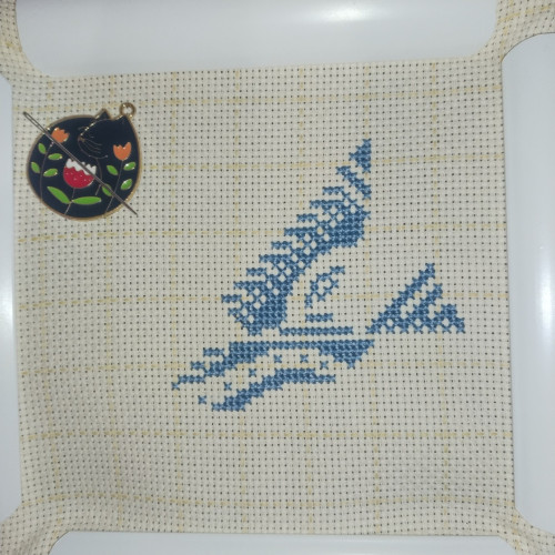 A work in progress cross stitch of a pigeon in flight